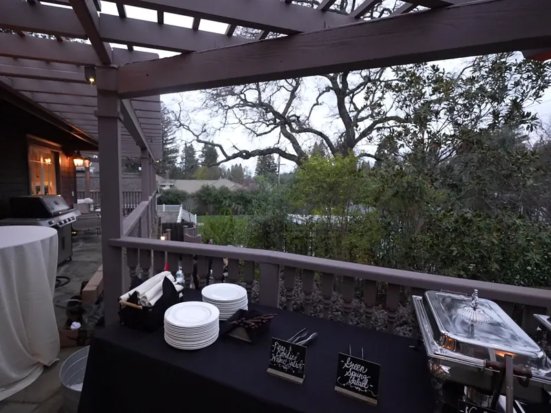 Deck buffet set under oak trees for a Palo Alto backyard gathering