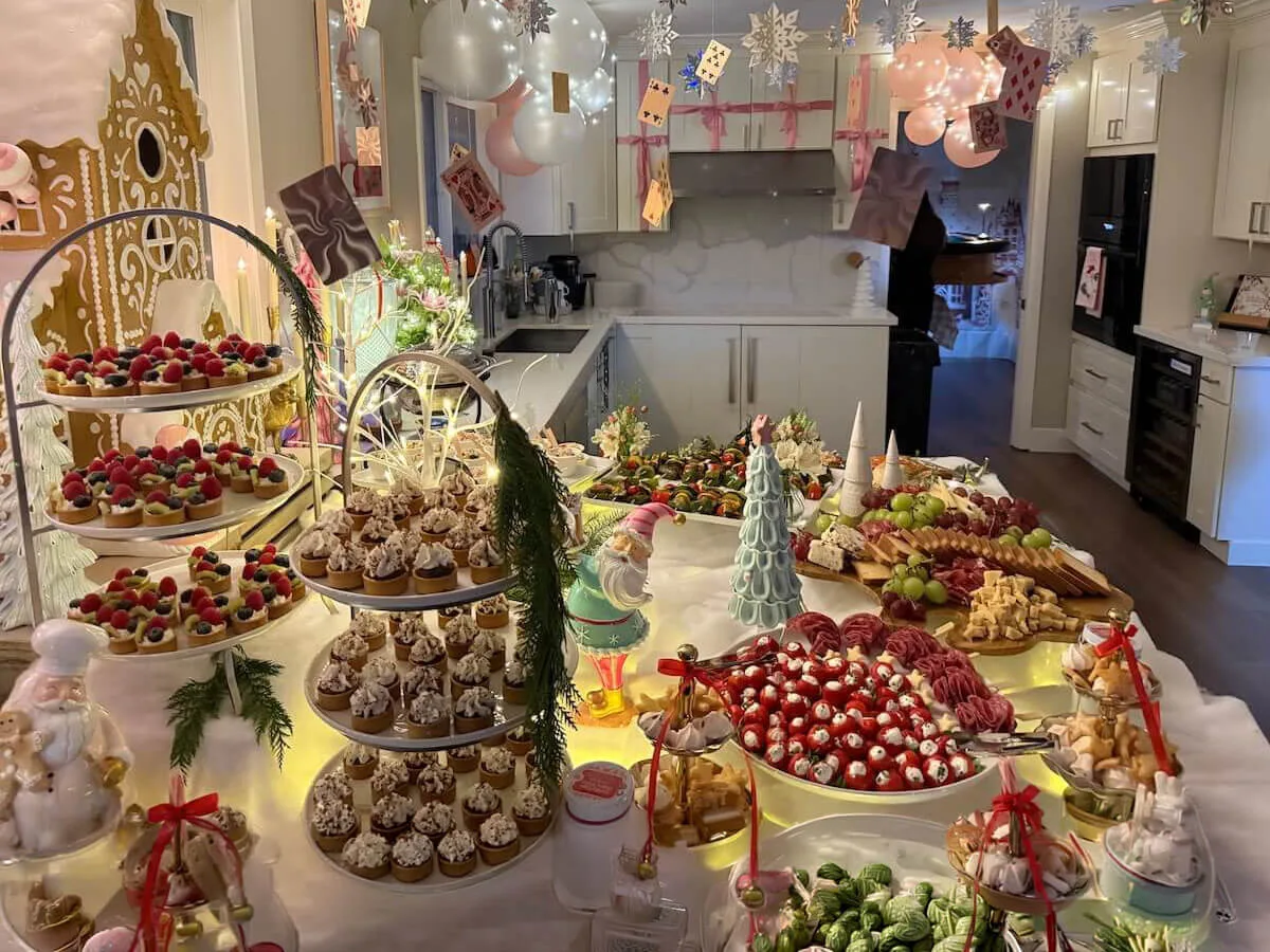 Styled tablescape of tiered tarts, frosted cupcakes and cured meats with pastel balloons drifting overhead